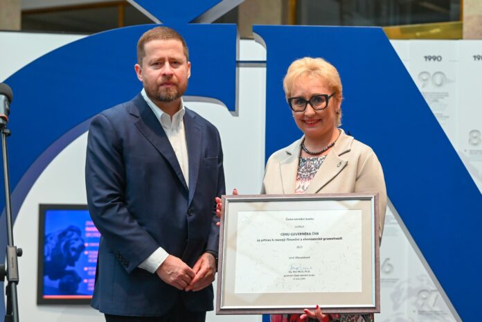 Jana Merunková přebírá ocenění od guvernéra Aleše Michla v prostorách Návštěvnického centra ČNB během slavnostního ceremoniálu 31. května 2025.