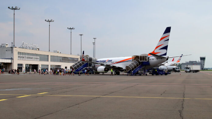 Letiště Leoše Janáčka Ostrava – letecký pohled na terminál s přistávajícím letadlem během rušné letní sezóny. Symbol růstu a mezinárodní propojenosti regionu.