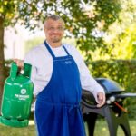 Plynový gril na zahradě s LPG láhví během letního víkendu
